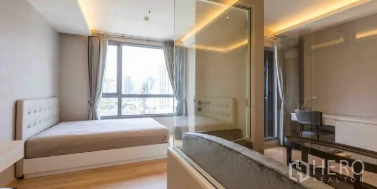 คอนโด ให้เช่าหรือขายในWatthana, Bangkok - ห้องนอนพร้อมหน้าต่างบานใหญ่เห็นวิวเมือง และผนังกระจกกั้นห้องน้ำที่มีอ่างอาบน้ำ