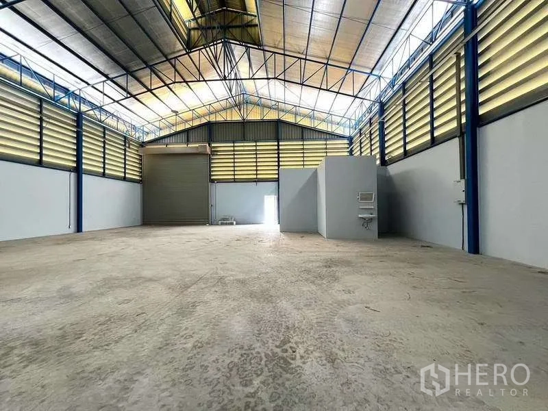 Warehouse for rent in Lat Lum Kaeo, Pathum Thani - Interior view toward loading door with restroom block and wall-mounted sink.