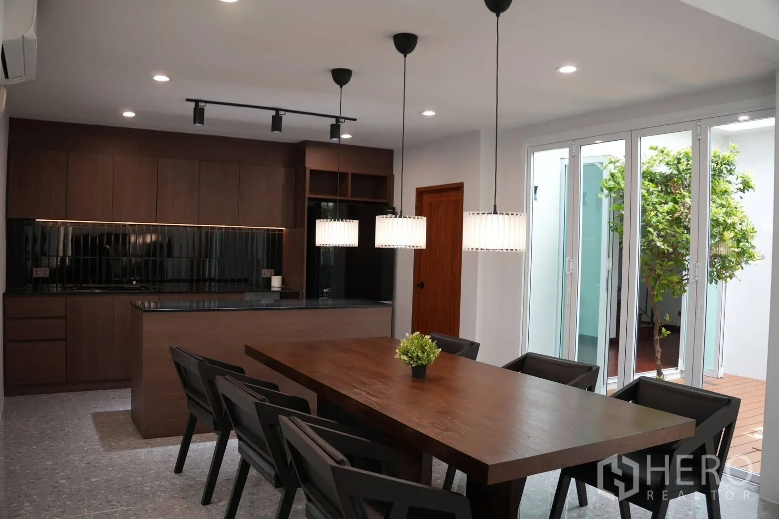 Detached House for rent in Suan Luang, Bangkok - Dining area with pendant lights beside sliding glass doors to the courtyard.