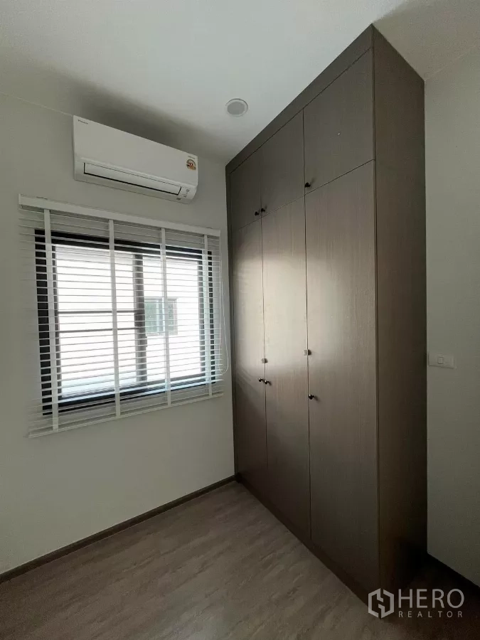 Detached House for rent or sale in Bang Phli, Samut Prakan - Bedroom corner with a tall built-in wardrobe, blinds, and air-conditioning unit.