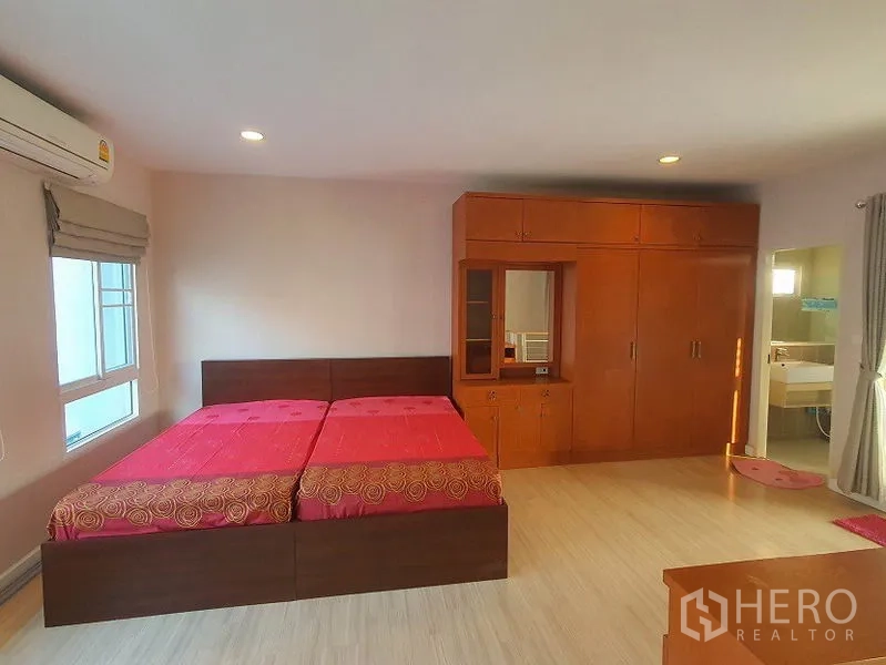 Townhouse for rent in Wang Thonglang, Bangkok - Master bedroom view showing double bed, cabinetry and door to bathroom.