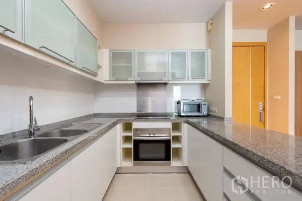 คอนโด ให้เช่าในKhlong Toei, Bangkok - ครัวรูปตัว U เคาน์เตอร์หินแกรนิต เตาอบ ไมโครเวฟ และตู้บานกระจก