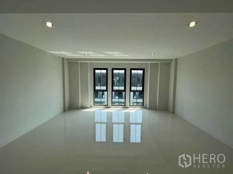 Home Office for rent - Sunlit room featuring three tall black-framed windows and polished flooring.