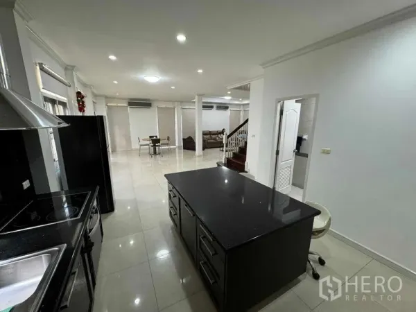 Detached House for rent in Prawet, Bangkok - Open-plan ground floor showing modern kitchen island, dining area and staircase.