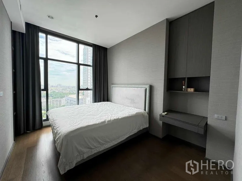 Condominium for sale in Bang Rak, Bangkok - Bedroom with tall windows, city view, blackout curtains and built‑in storage desk.