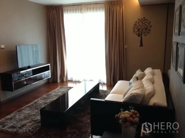 Condominium for rent in Watthana, Bangkok - Cozy living room with long coffee table, TV console, large window with curtains and a shaggy rug.