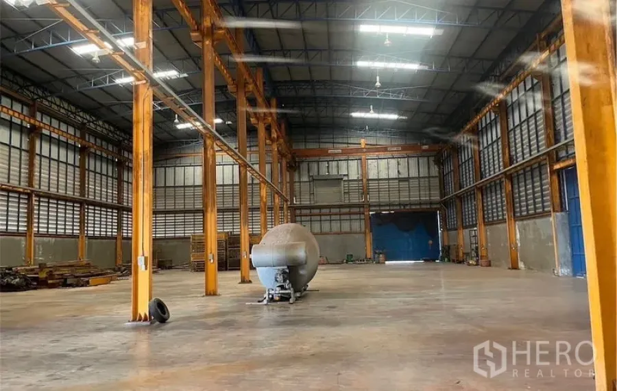 Factory for rent in Samut Songkhram - Wide warehouse hall with skylights, ventilation louvers, crane beam rails and large blue sliding doors in Amphawa.