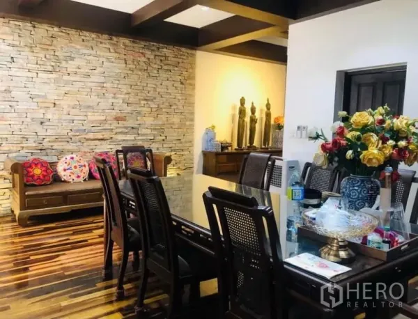 Condominium for rent in Pathum Wan, Bangkok - Formal dining area with a glass-top table, rattan-backed chairs and a stacked-stone accent wall.