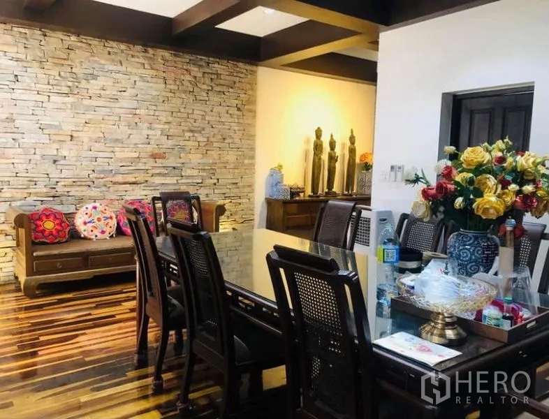 Condominium for rent in Pathum Wan, Bangkok - Formal dining area with a glass-top table, rattan-backed chairs and a stacked-stone accent wall.