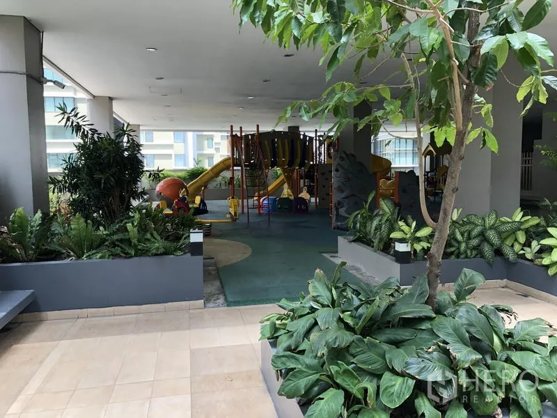 อพาร์ทเมนท์ ให้เช่าในKhlong Toei, Bangkok - สนามเด็กเล่นในร่มมีสไลเดอร์และเครื่องเล่น ล้อมด้วยต้นไม้เขียวขจีในพื้นที่ส่วนกลางของอพาร์ตเมนต์