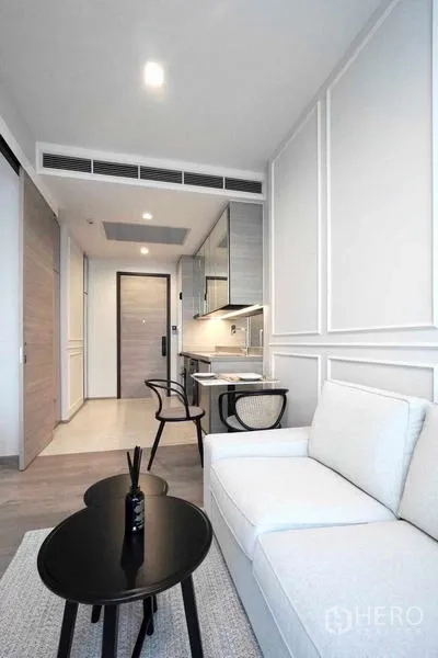 คอนโด ให้เช่า - พื้นที่นั่งเล่นสว่างพร้อมโซฟา ครัวบิลต์อิน และโต๊ะทานข้าวในคอนโด 1 ห้องนอน.