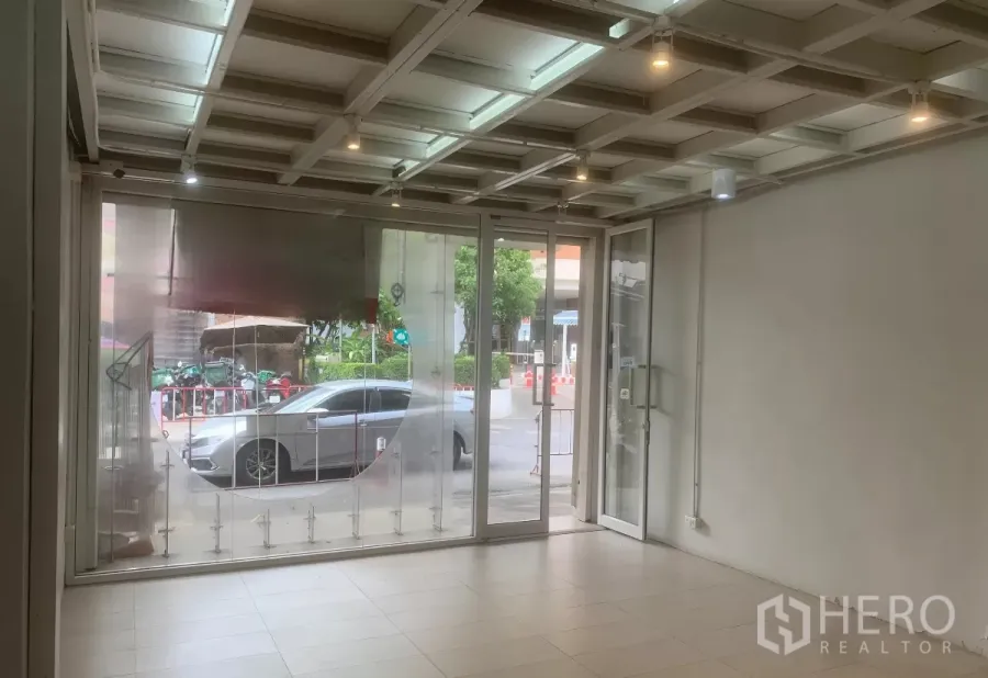 零售空间 出租在Yan Nawa, Bangkok - 临街玻璃门面的明亮店铺，室内瓷砖地面与射灯，可见街景。