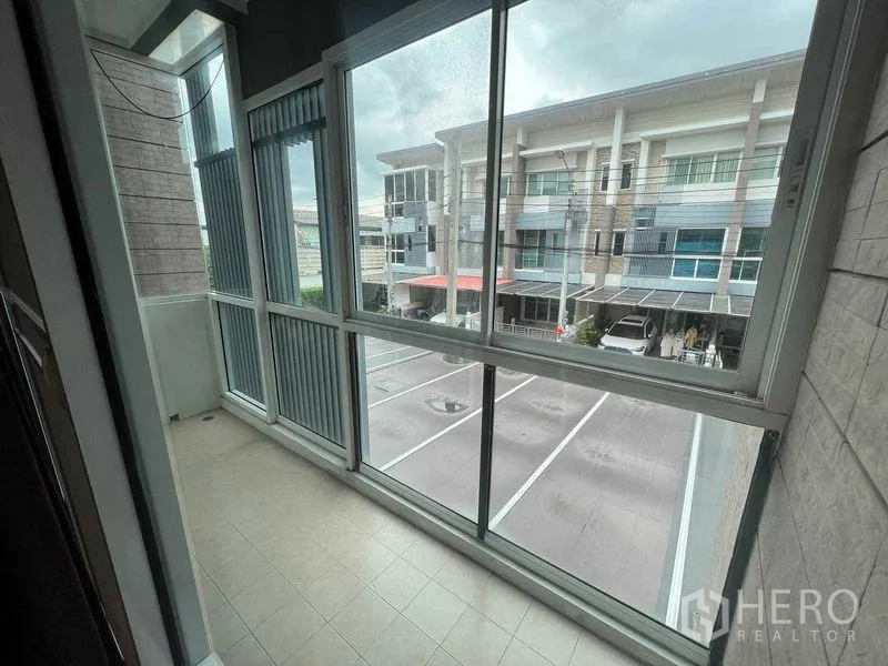 ทาวน์เฮาส์ ให้เช่าในBueng Kum, Bangkok - ระเบียงกระจกปิดทึบ มองเห็นแถวทาวน์โฮมและลานจอดรถ