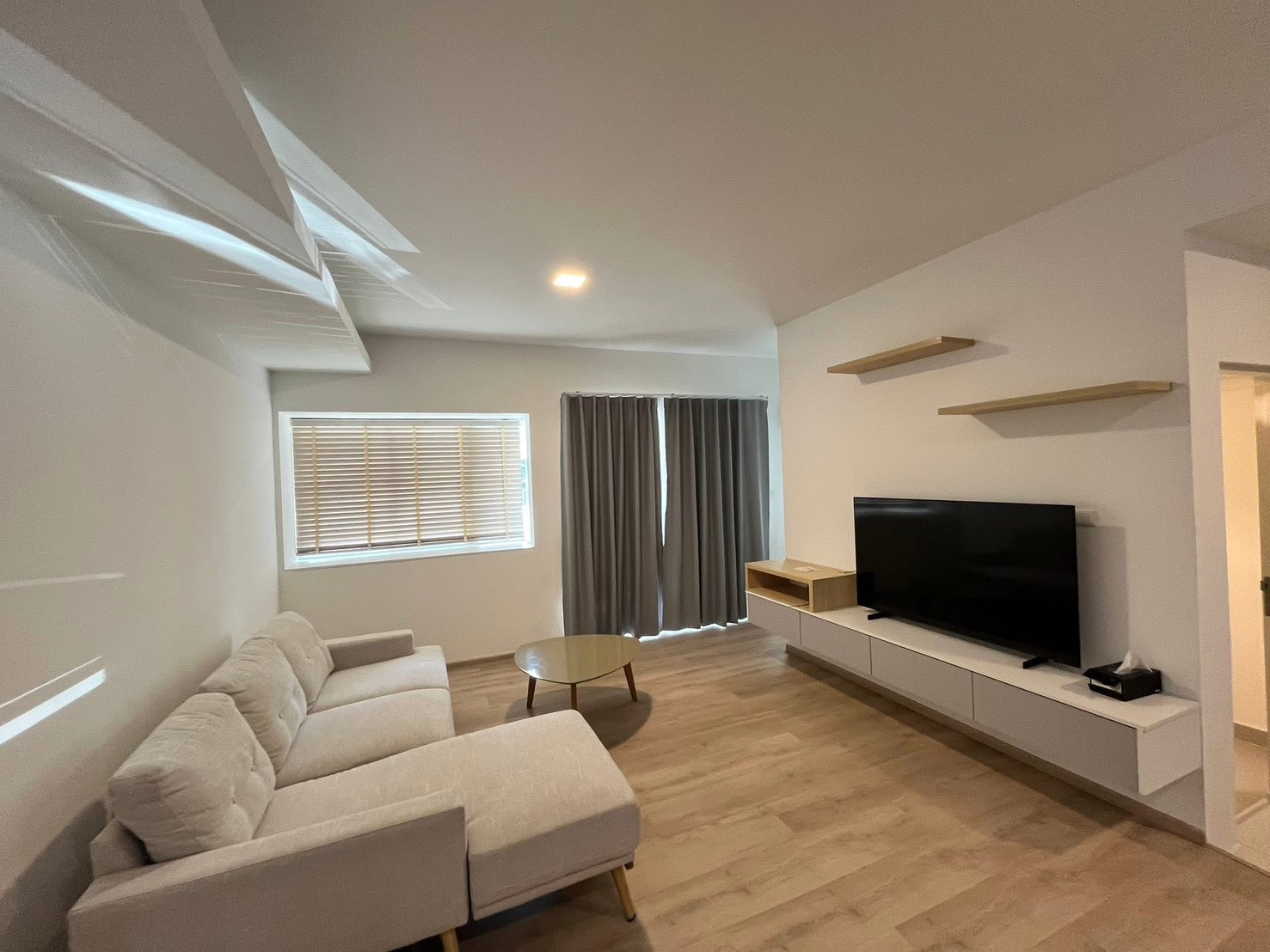 联排别墅 for rent in Prawet, Bangkok - 明亮客厅，L形沙发，壁挂电视与储物柜。