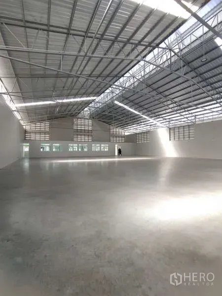 Warehouse for rent in Bang Pakong, Chachoengsao - Spacious warehouse interior with high steel truss ceiling and polished concrete floor.