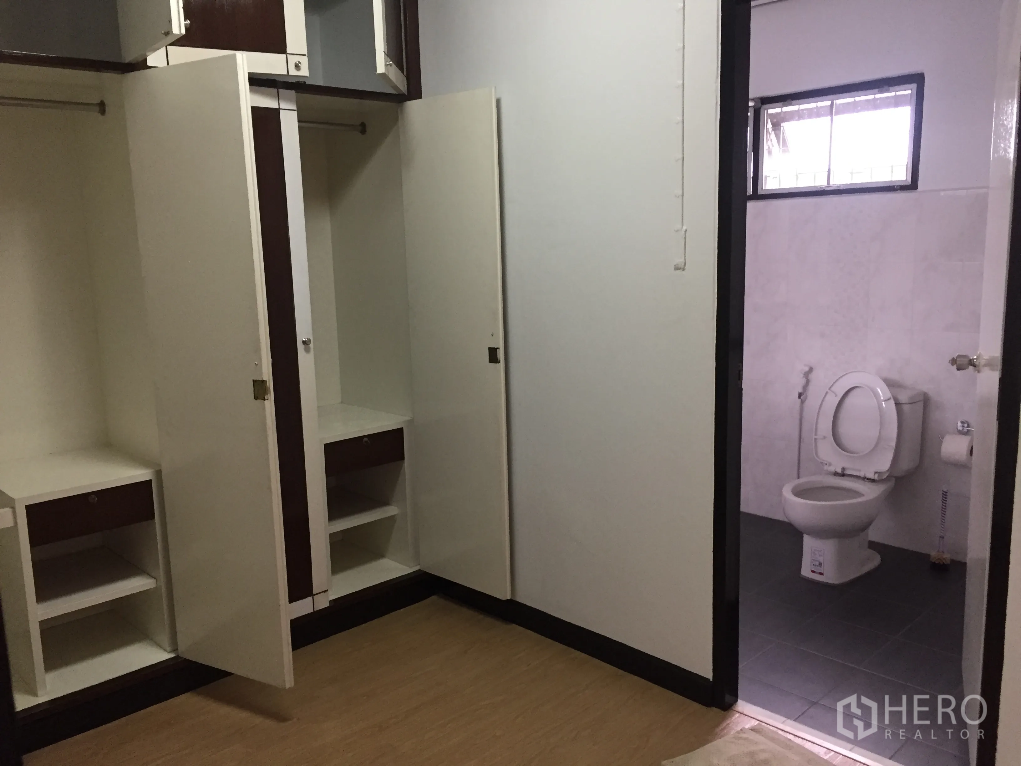 Townhouse for rent in Khlong Toei, Bangkok - Bedroom with open built-in wardrobes and a doorway leading to a tiled bathroom.