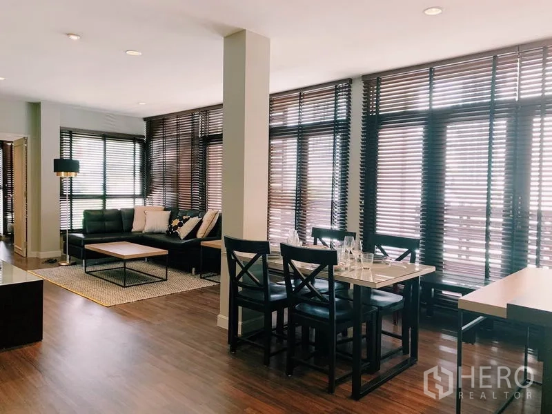 คอนโด ให้เช่าในWatthana, Bangkok - โถงรับแขกและรับประทานอาหารแบบโอเพ่น แบล็กโซฟาหนัง ชุดโต๊ะกินข้าว และหน้าต่างเต็มผนังพร้อมมู่ลี่ไม้