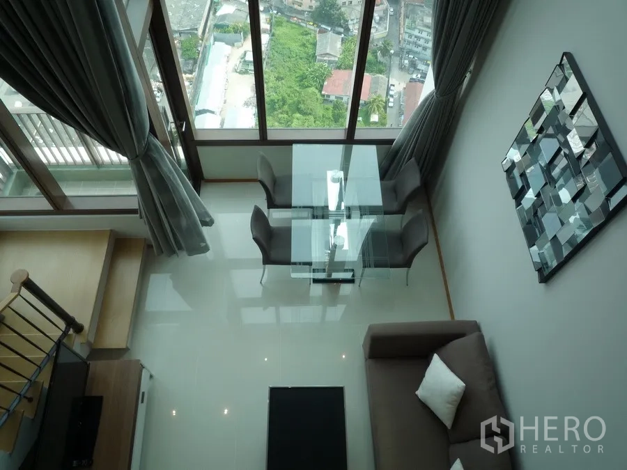 คอนโด ให้เช่าในKhlong Toei, Bangkok - มุมมองจากด้านบนของโต๊ะอาหารกระจกติดหน้าต่างสูงและระเบียงในคอนโดดูเพล็กซ์