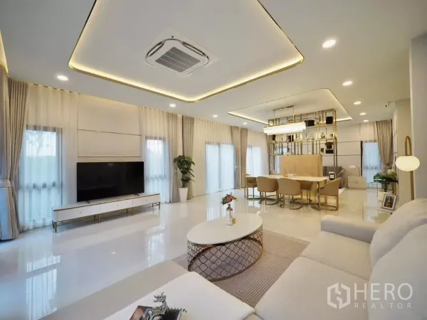 Detached House for rent in Bang Phli, Samut Prakan - Open-plan living and dining area with TV wall, chandelier and full-height curtains.