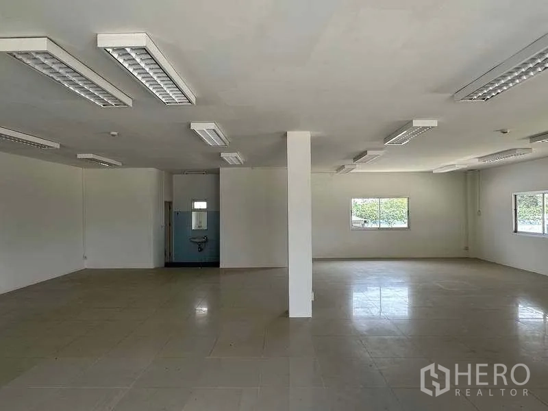 Warehouse for rent in Samut Prakan - Open-plan office space with fluorescent lighting and tiled flooring.