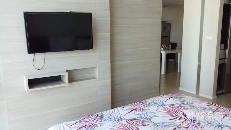 Condominium for rent in Watthana, Bangkok - Bedroom feature wall with mounted flat-screen TV and light wood paneling.