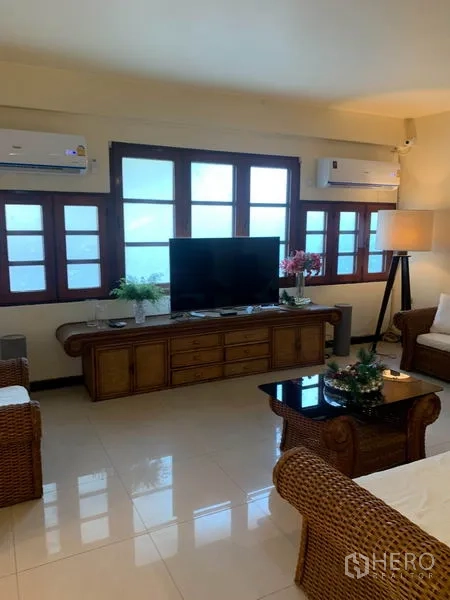 ทาวน์เฮาส์ ให้เช่าหรือขายในPhra Khanong, Bangkok - ห้องนั่งเล่นติดแอร์ ชุดโซฟาหวาย ชั้นวางทีวี และผนังหน้าต่างบานยาว