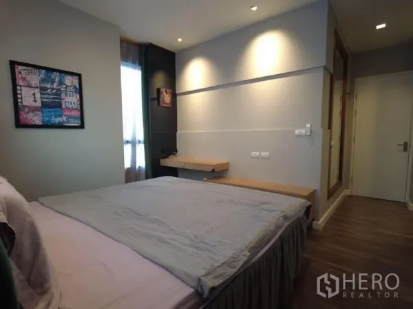 Condominium for rent in Watthana, Bangkok - Cozy bedroom with wall lights, floating desk and wood flooring.