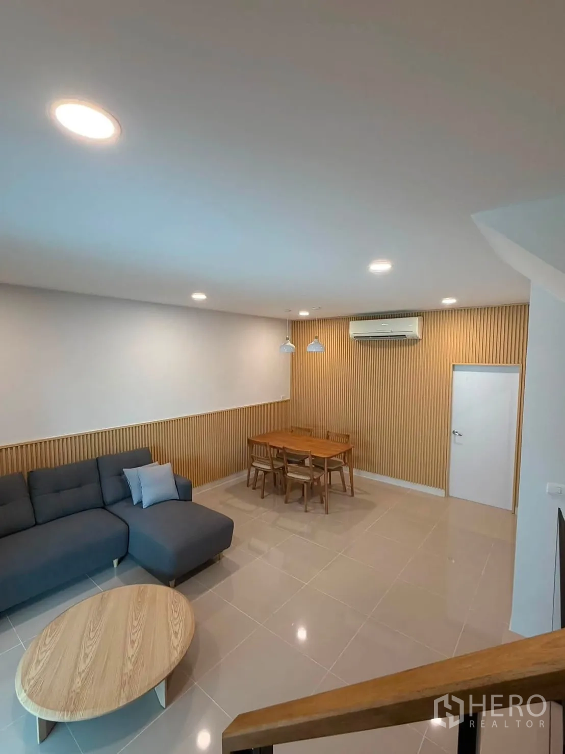 Townhouse for rent in Bang Phli, Samut Prakan - Living and dining area with wood slat feature wall and ceiling lights.