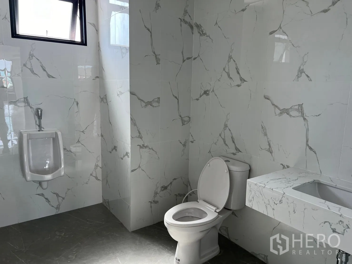 货栈 出租在Samut Prakan - 卫生间铺大理石纹瓷砖，配坐便器、小便器与台盆。
