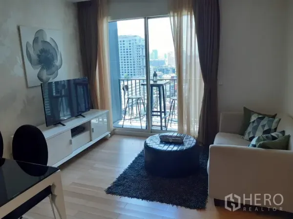 คอนโด ให้เช่าในKhlong Toei, Bangkok - ห้องนั่งเล่นสว่าง โซฟา ทีวี และประตูบานเลื่อนออกสู่ระเบียงวิวเมือง