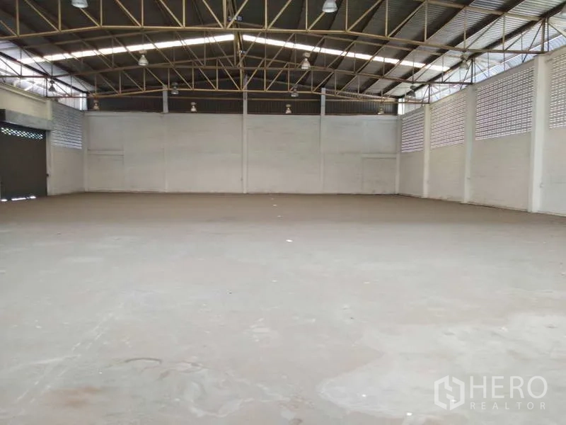 Warehouse for rent in Bang Phli, Samut Prakan - Expansive factory floor with high roof trusses and roller doors along the side wall.