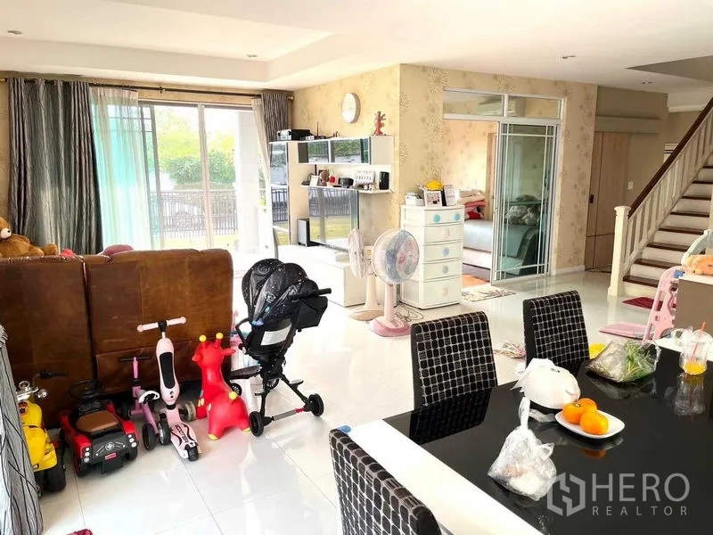 บ้าน ขายในSamut Prakan - พื้นที่นั่งเล่นและทานอาหารแบบโอเพ่น มีประตูกระจกบานเลื่อน พื้นกระเบื้องเงา และบันไดขึ้นชั้นบน