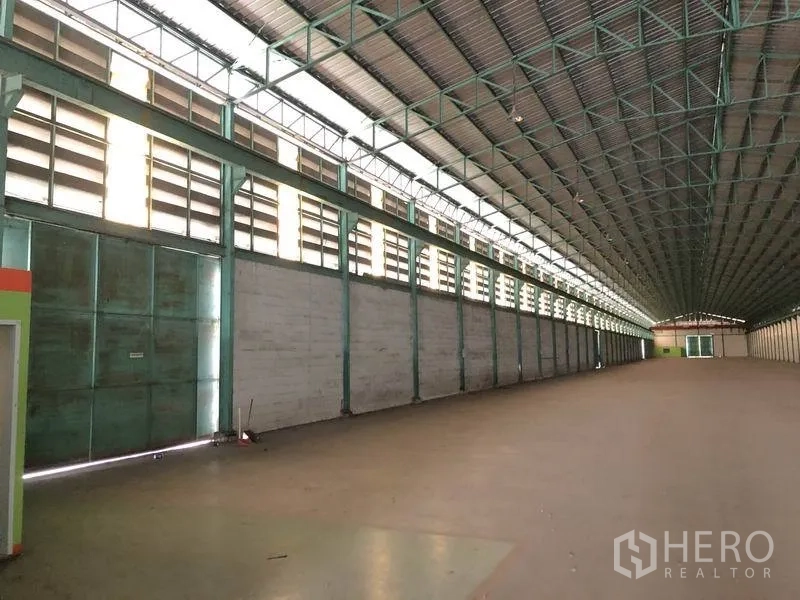 Warehouse for rent in Samut Prakan - Interior side wall featuring large sliding steel doors and louvered ventilation.