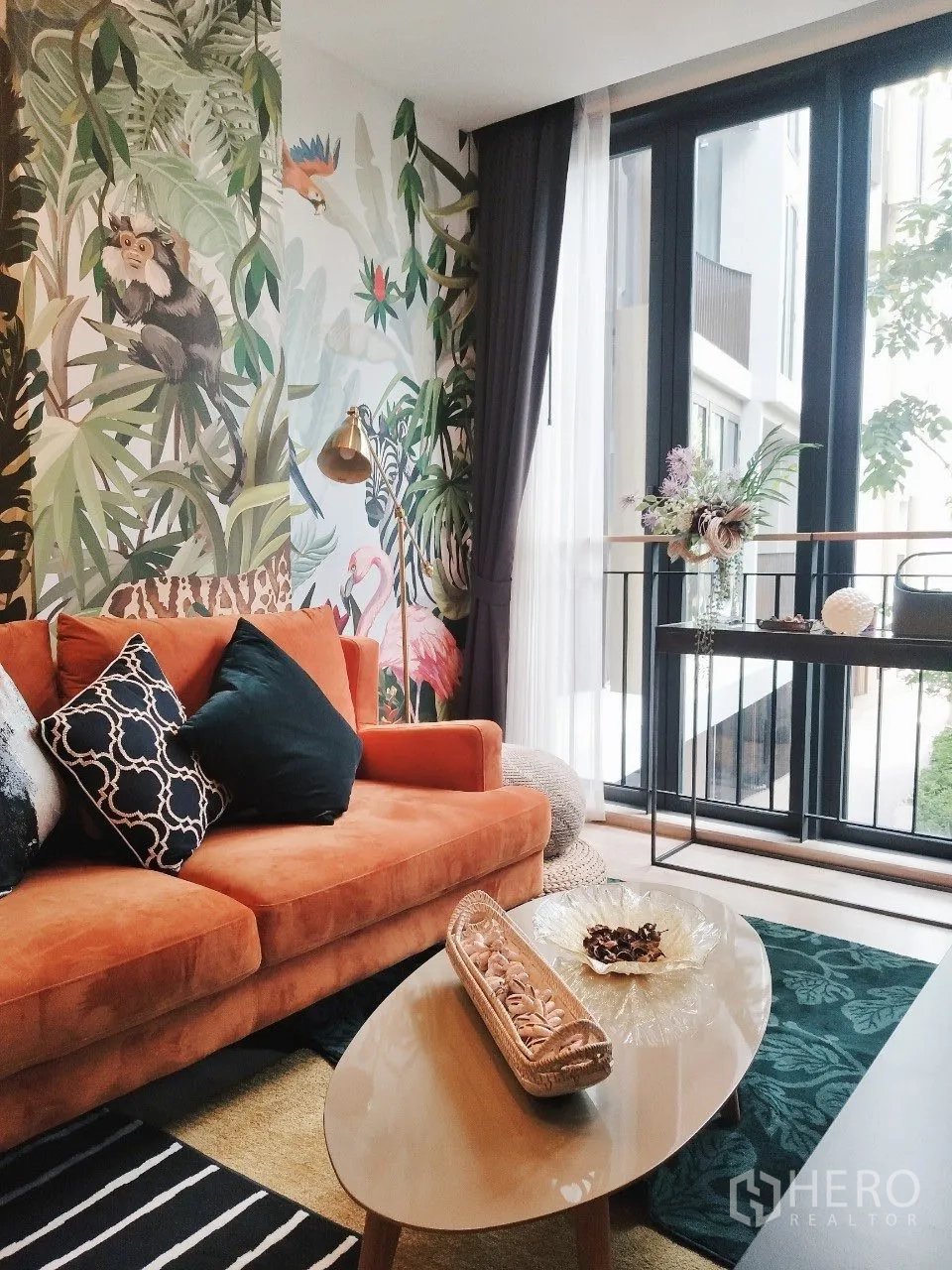 公寓 for rent in Watthana, Bangkok - 客厅配橙色沙发、热带风壁画、茶几与大窗。