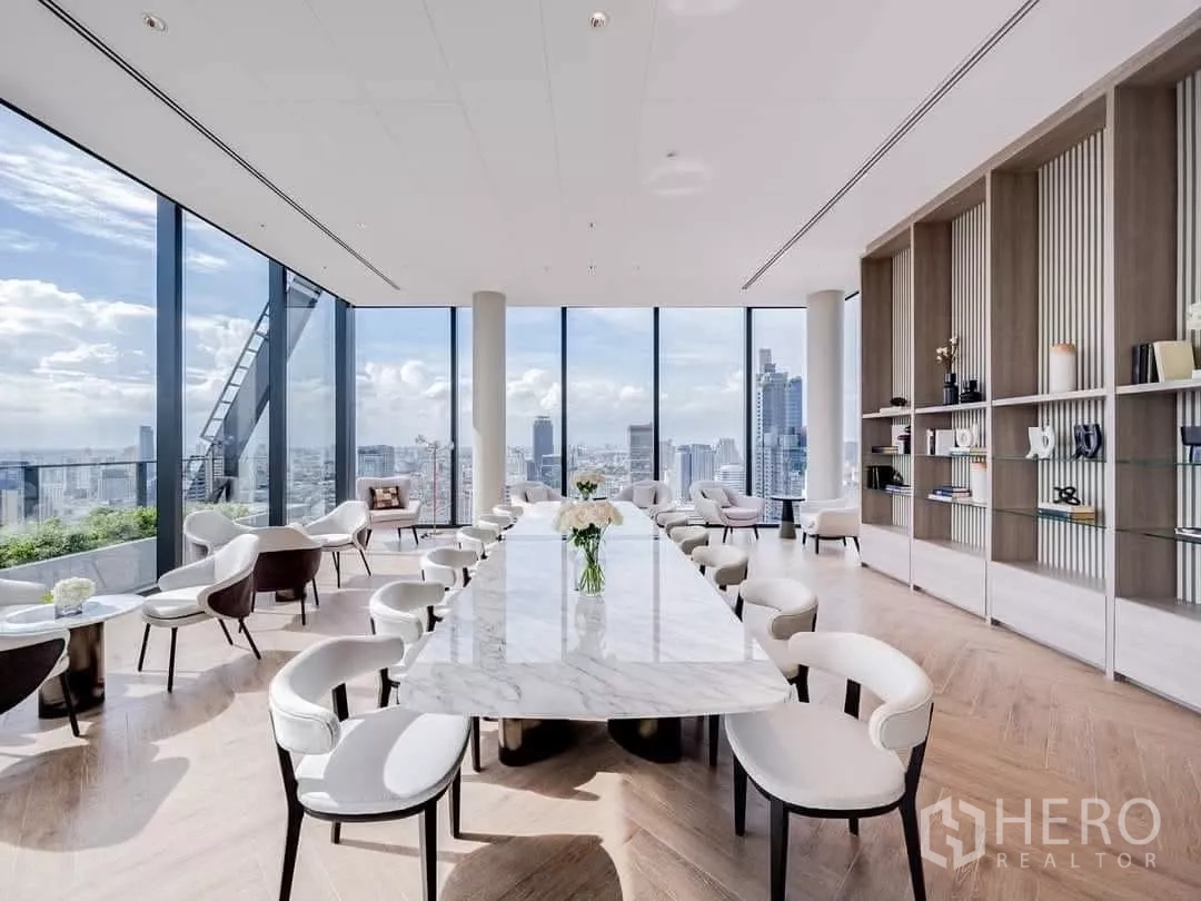 公寓 出租在Bang Rak, Bangkok - 明亮的空中会所与共享办公区，长条大理石餐桌与全景窗。