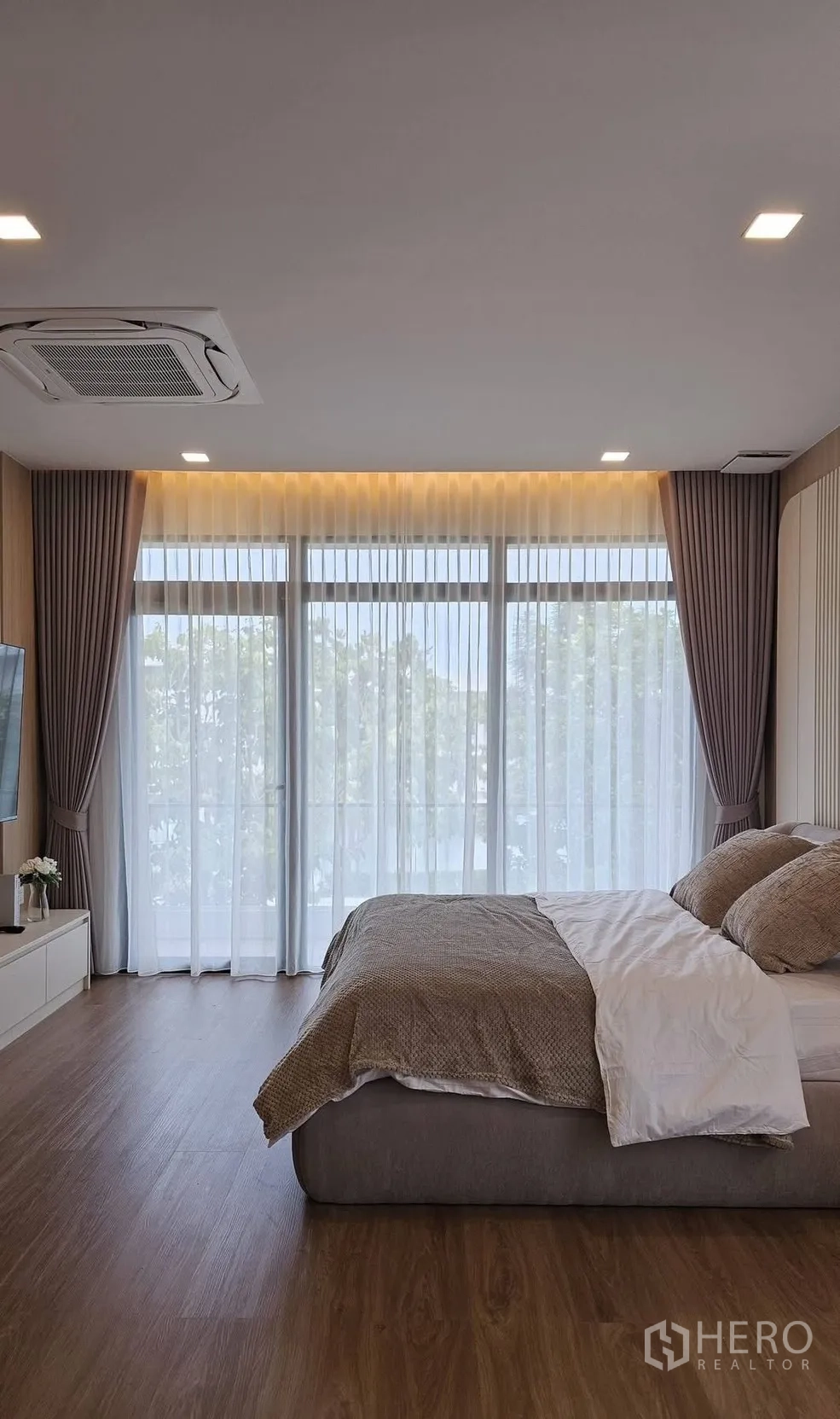 บ้านเดี่ยว for rent in Bang Phli, Samut Prakan - ห้องนอนหลักมีหน้าต่างกระจกกว้าง ผ้าม่านโปร่ง และเตียงคิงไซส์บนพื้นไม้.