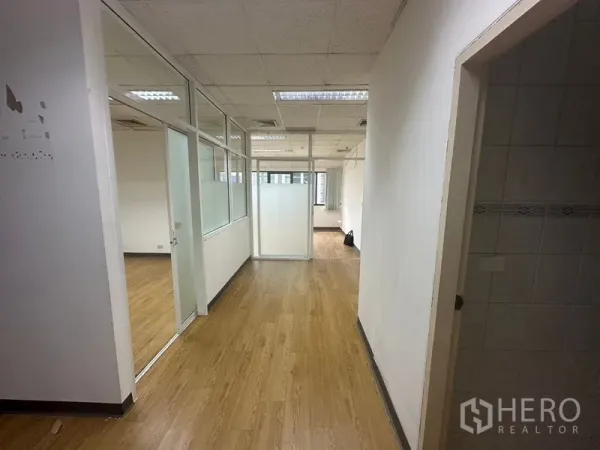 办公空间 出租在Watthana, Bangkok - 玻璃隔间走廊，木纹地板与吊顶照明的办公空间。