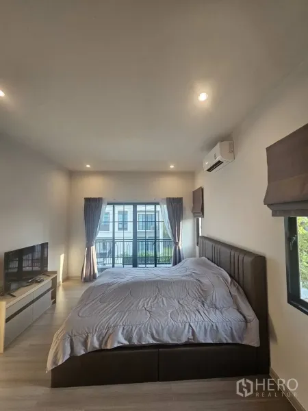 Detached House for rent in Khlong Sam Wa, Bangkok - Spacious master bedroom with king bed, balcony doors and air conditioning.