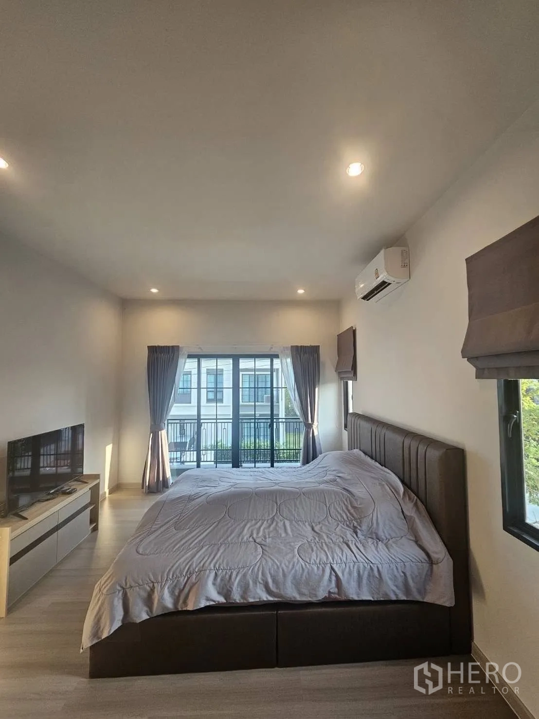 Detached House for rent in Khlong Sam Wa, Bangkok - Spacious master bedroom with king bed, balcony doors and air conditioning.