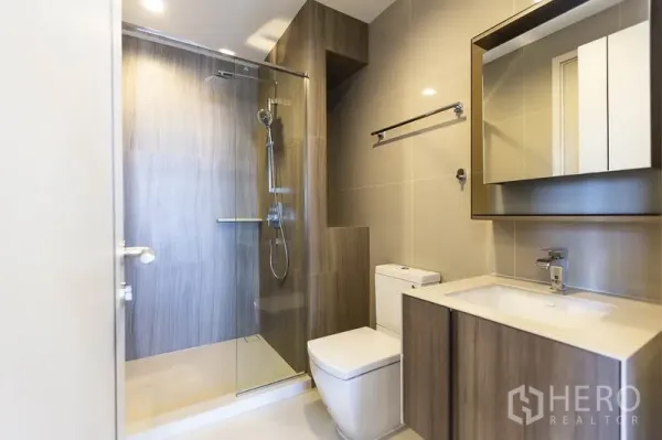 คอนโด ให้เช่าในPhaya Thai, Bangkok - ห้องน้ำโมเดิร์นพร้อมตู้กระจกอาบน้ำ เคาน์เตอร์อ่างล้างหน้า และกระเบื้องโทนอบอุ่น