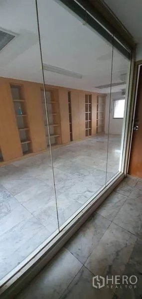 Home Office for rent in Watthana, Bangkok - Glass-partitioned office room with marble floor and built-in shelving.