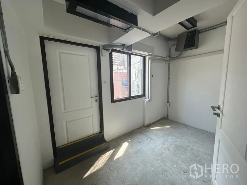 Home Office for rent in Phra Khanong, Bangkok - Compact utility room with a window, white doors and exposed ducting.