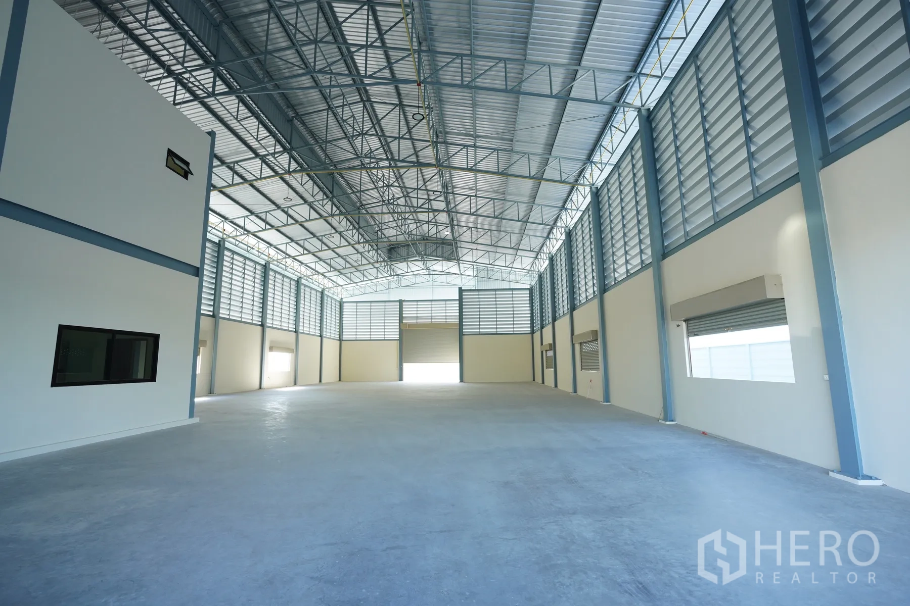 Factory for rent in Mueang Samut Prakan, Samut Prakan - Open production area with polished concrete floor, natural light, and a large roller shutter door.
