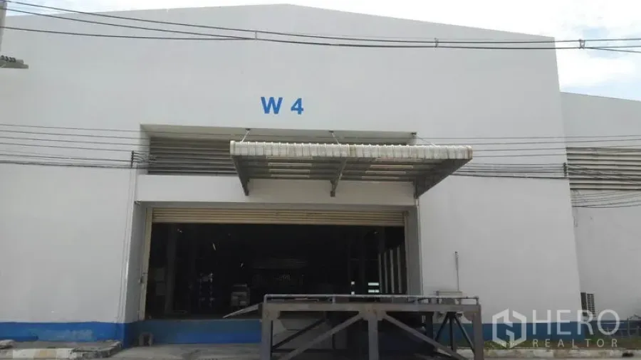Factory for rent in Chachoengsao - White factory exterior with roll-up shutter, covered loading dock, and W4 signage.