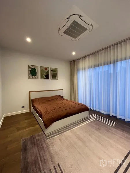 Detached House for rent in Bang Kapi, Bangkok - Bedroom with brown duvet, ceiling cassette AC and wide sheer curtains