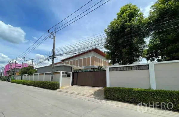 工厂 出售在Krathum Baen, Samut Sakhon - 街景视角的封闭式工业物业，高外墙与树木