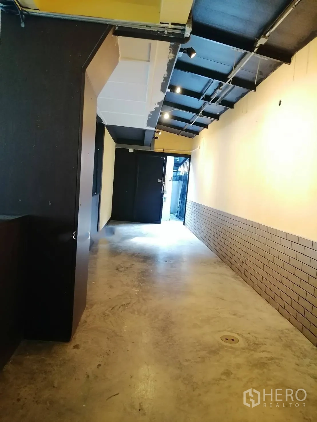 Detached House for rent in Watthana, Bangkok - Long hallway with exposed ceiling track lights and polished concrete flooring.