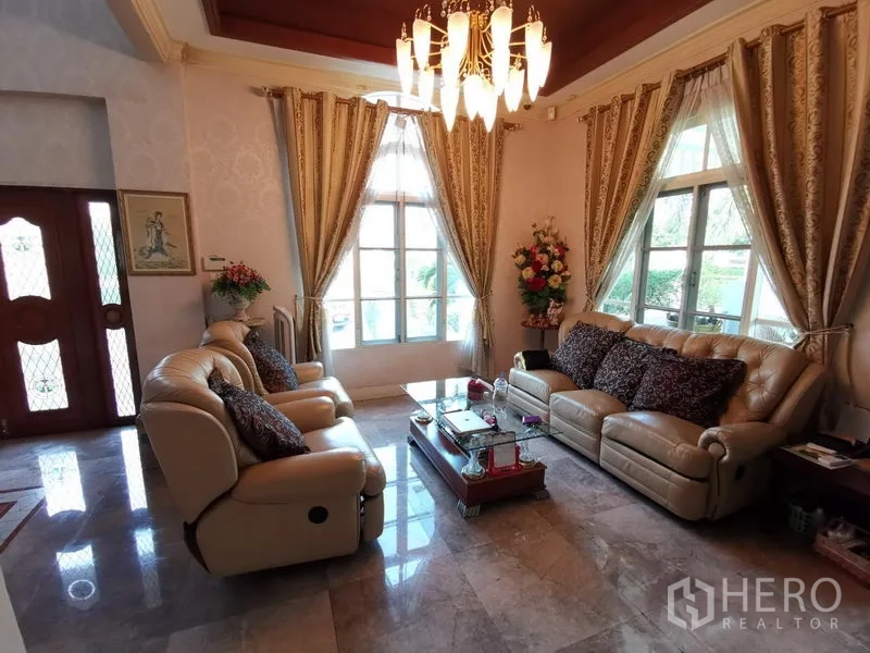 独立式住宅 出售在Phra Khanong, Bangkok - 正式客厅，大窗与华丽窗帘，皮沙发布置典雅。