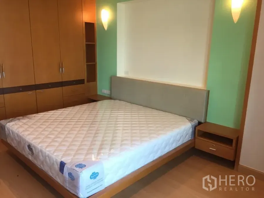 Condominium for rent in Sathon, Bangkok - Bright bedroom with queen bed, built-in wooden wardrobes and wall sconces.