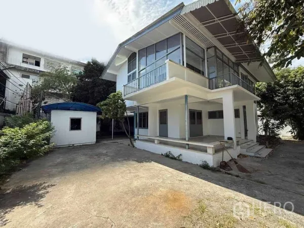 独立式住宅 出租在Watthana, Bangkok - 白色两层住宅外观一角，设有阳台与有顶露台。